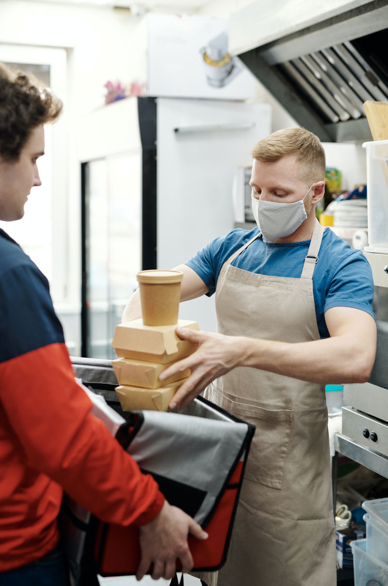 Store employee handing over take out food to delivery driver